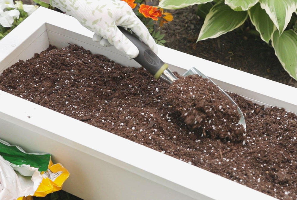 shovel scooping fertilizer dirt into white box