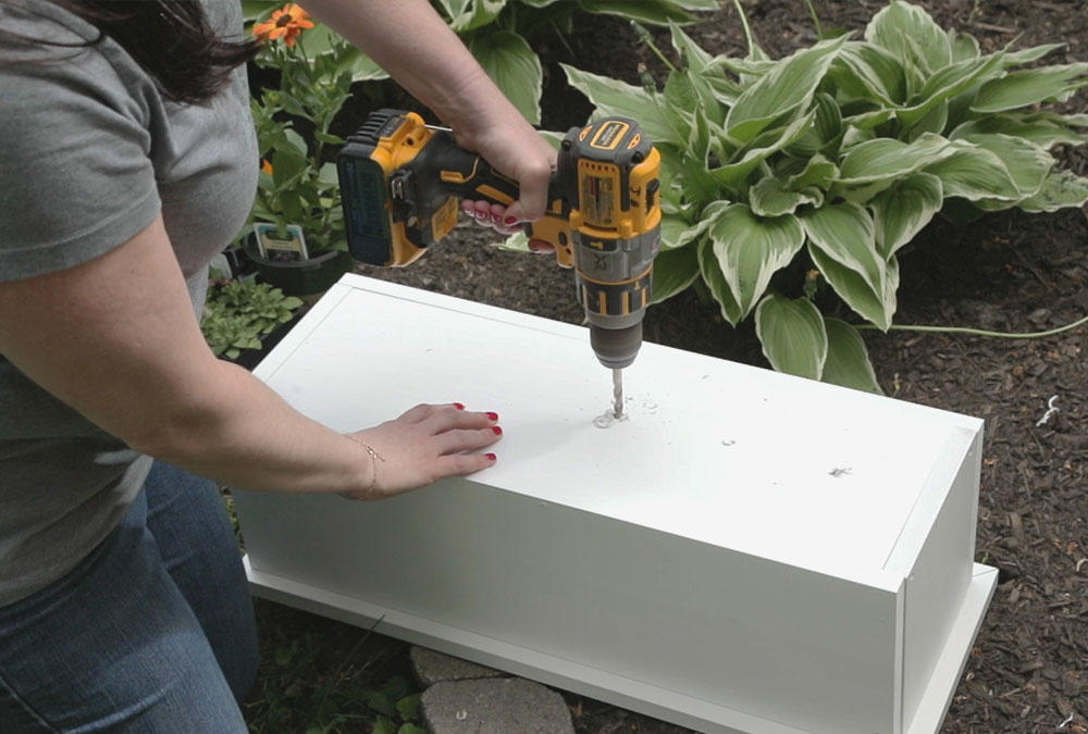 woman drilling a hole into the bottom of a white box