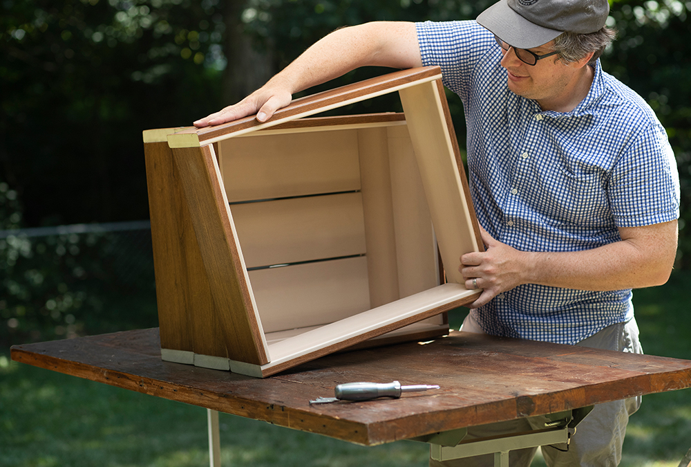 person assembling wood into a square box shape